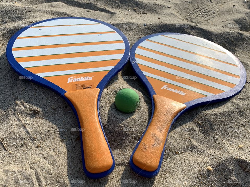 Enjoyable Kadima game for all ages. Sand and beach. Afternoon, green ball, orange and blue paddle game.