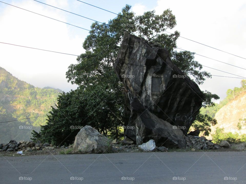 Large mountain rocks on the side of the road in a hilly area, there are inscriptions on the stone.