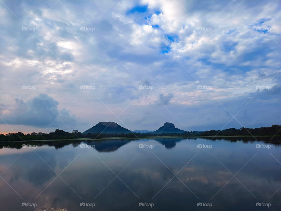 Mornig view of majestic Sigiriya rock fortress and Pidurangala rock from a distance with reflection on a near by lake. Seing double.