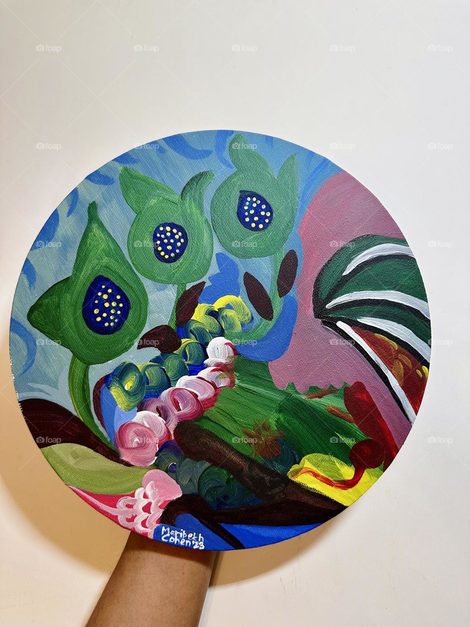 A person holding of close up photo of abstract acrylic painting on canvas against white backdrop.