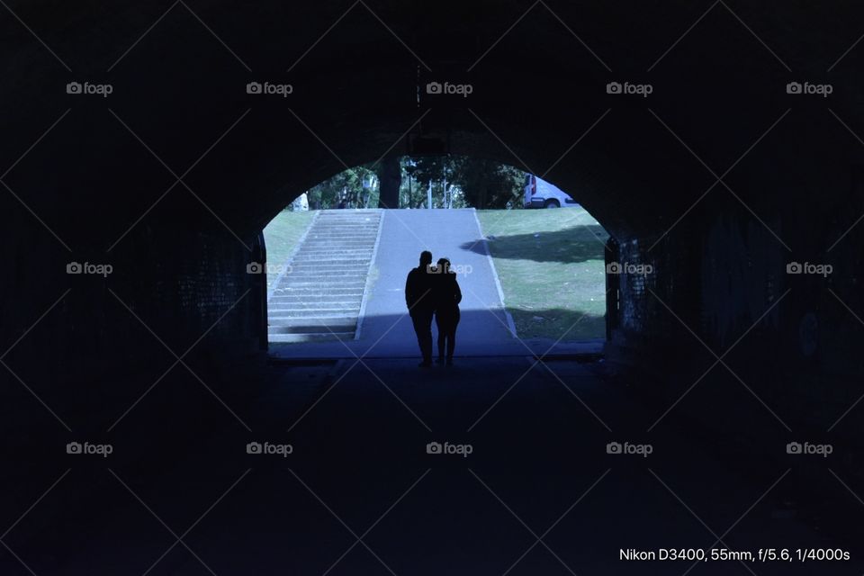 Una pareja caminando lentamente por un túnel 