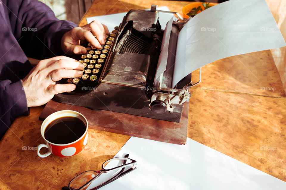 A young writer is writing his new book on his old typewriter.