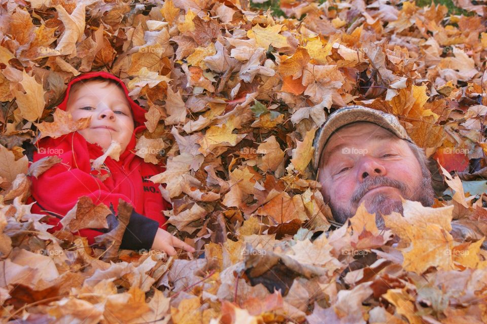 Father and son lying on autumn leaf