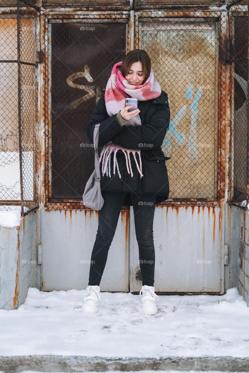 Young woman with mobile phone in white Dr. Martens boots in winter 