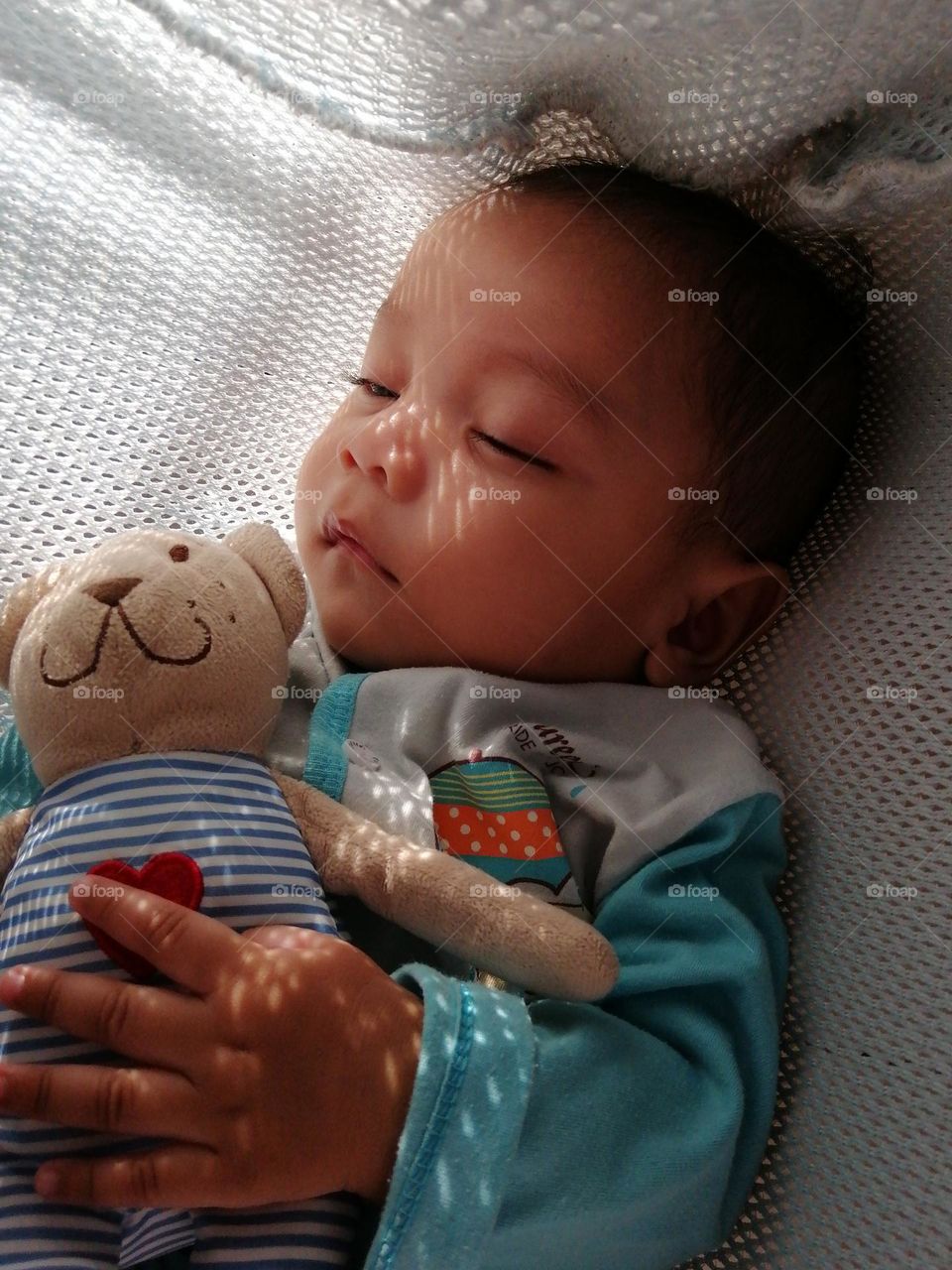 a little boy sleeps with his favorite little soft bear.