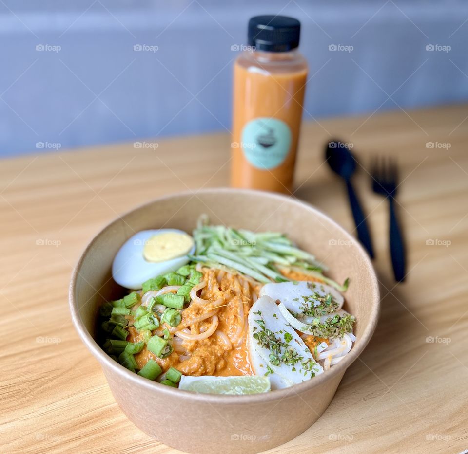 Khanom jeen namya thailand dry laksa fish with fish curry, boiled egg, fresh greens and fishcake slices and Thai milk tea 