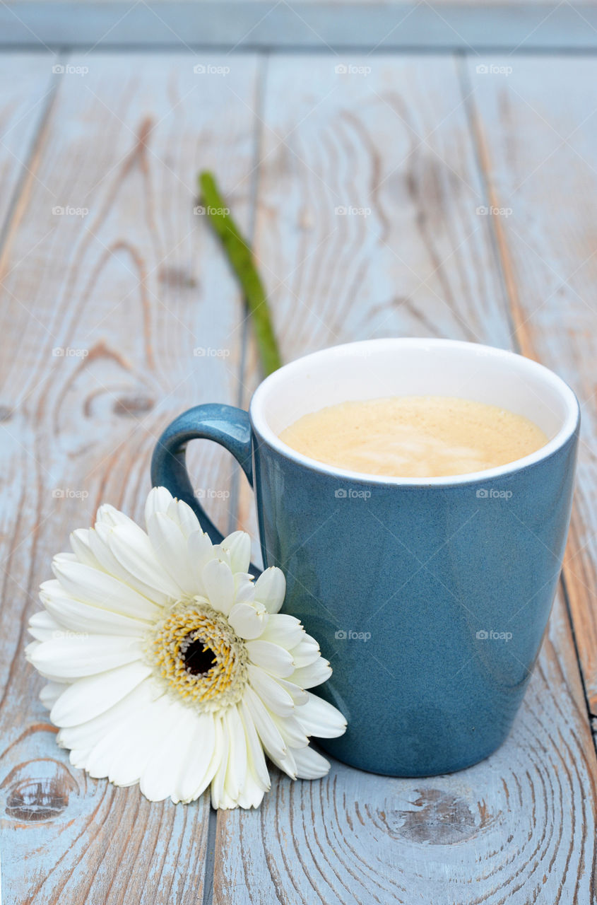 cup of coffee on a wooden background with white daisy flower
 decoration