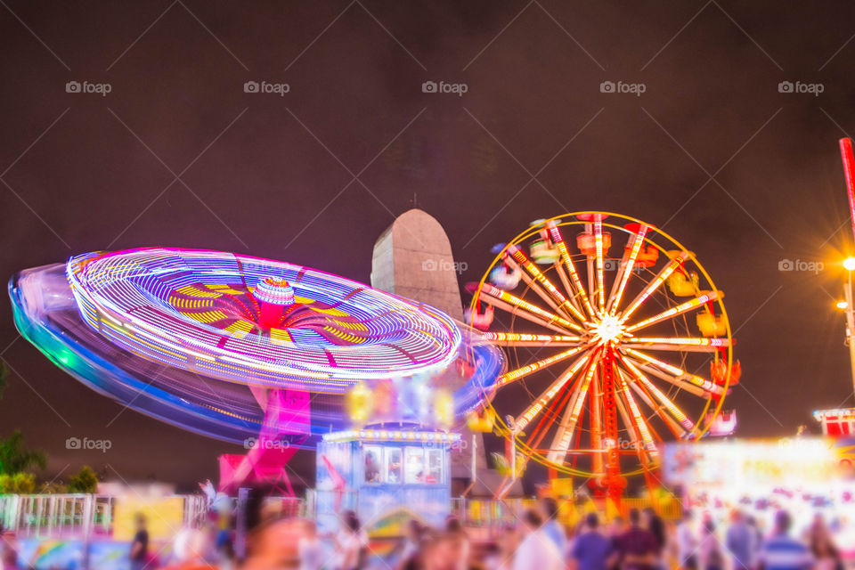 Spinning wheels at amusement park with colorful lights