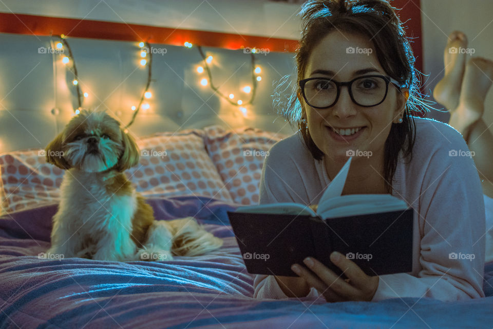 Cute girl reading in bed with her dog