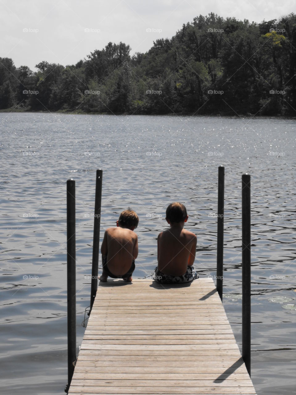 Two boys sitting on the end of the pier