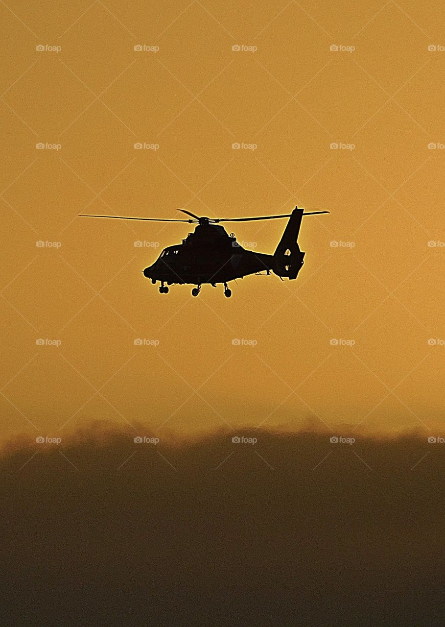 Coast Guard helicopter flying on a rescue mission through the sunset over the Gulf of Mexico 