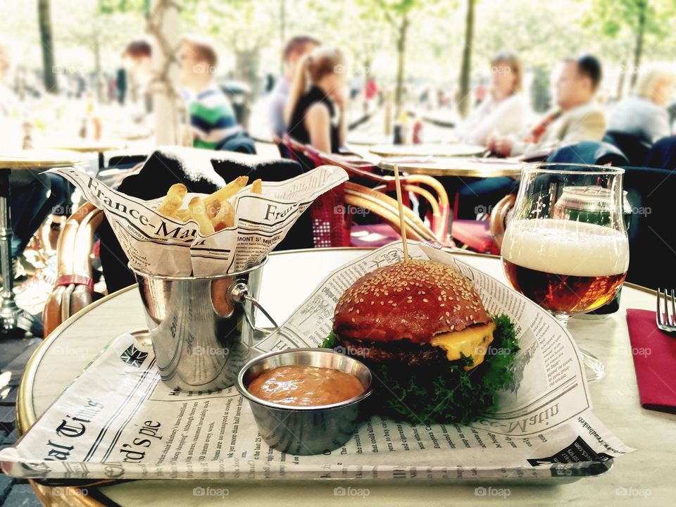 Lunch time. Burger, fries and beer on the table of open terrace cafe