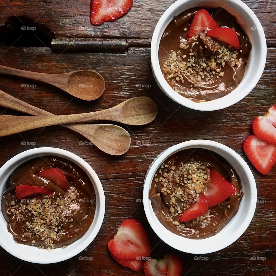 Chocolate avocado mousse with crumb topping in white bowls on wood table.