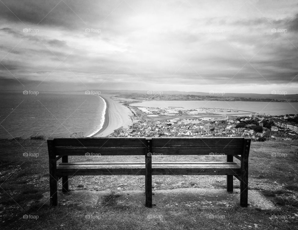 Beam of light on park bench overlooking Weymouth harbour. 
