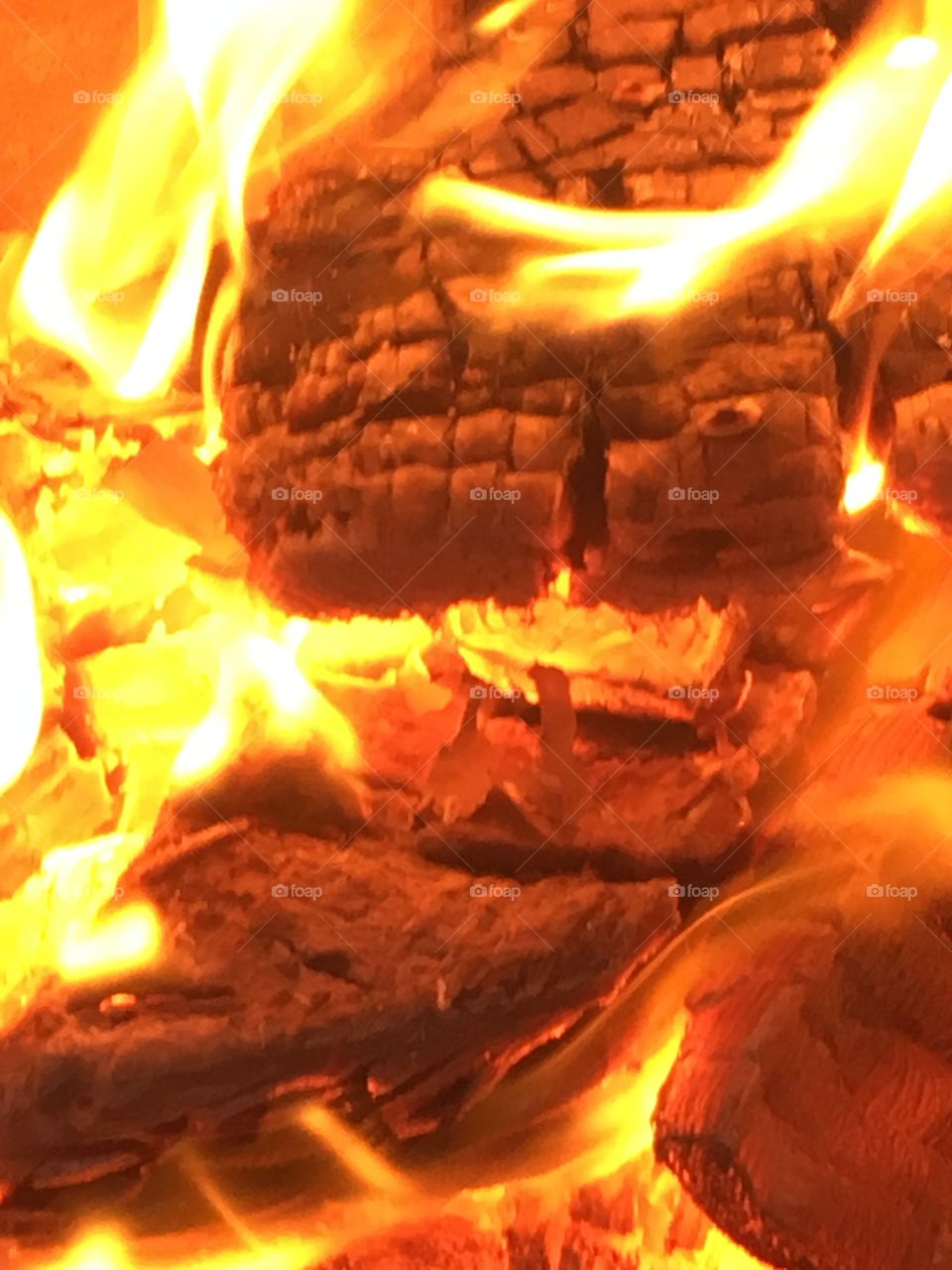 Wooden logs burning with flames in close up in a chiminea in the garden 