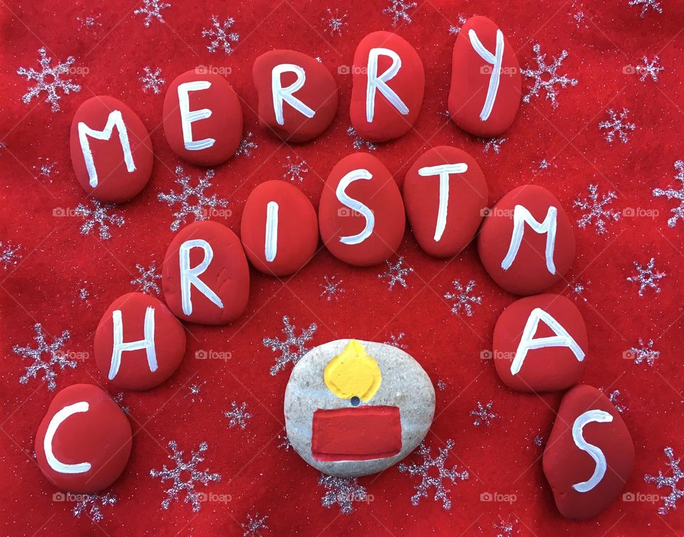 Merry Christmas with candle, stones composition on a red carpet