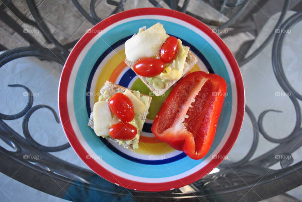 Preparing small bites with peppers, cherry tomatoes, avocado and cheese