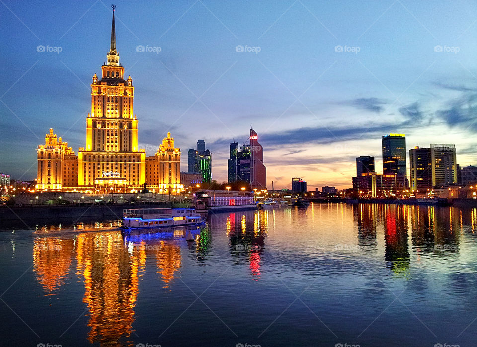the city reflects in the river in the evening lights