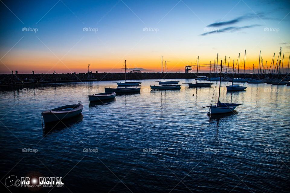 Boats floating in the marina along St.Kilda Pier at sunset, that beautiful transition of blue to pink to orange and subtle ripple in the water and deep shadow.