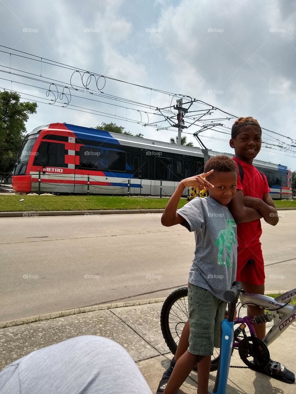 Two brothers👨‍👦 posing for a picture while a Metro rail 🚆 train on its way to the station passes in the background.
