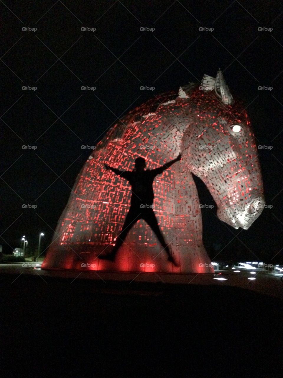 Photo taken with my old iPhone of my son jumping in the air against a red lit up background of one of The Kelpies ❤️