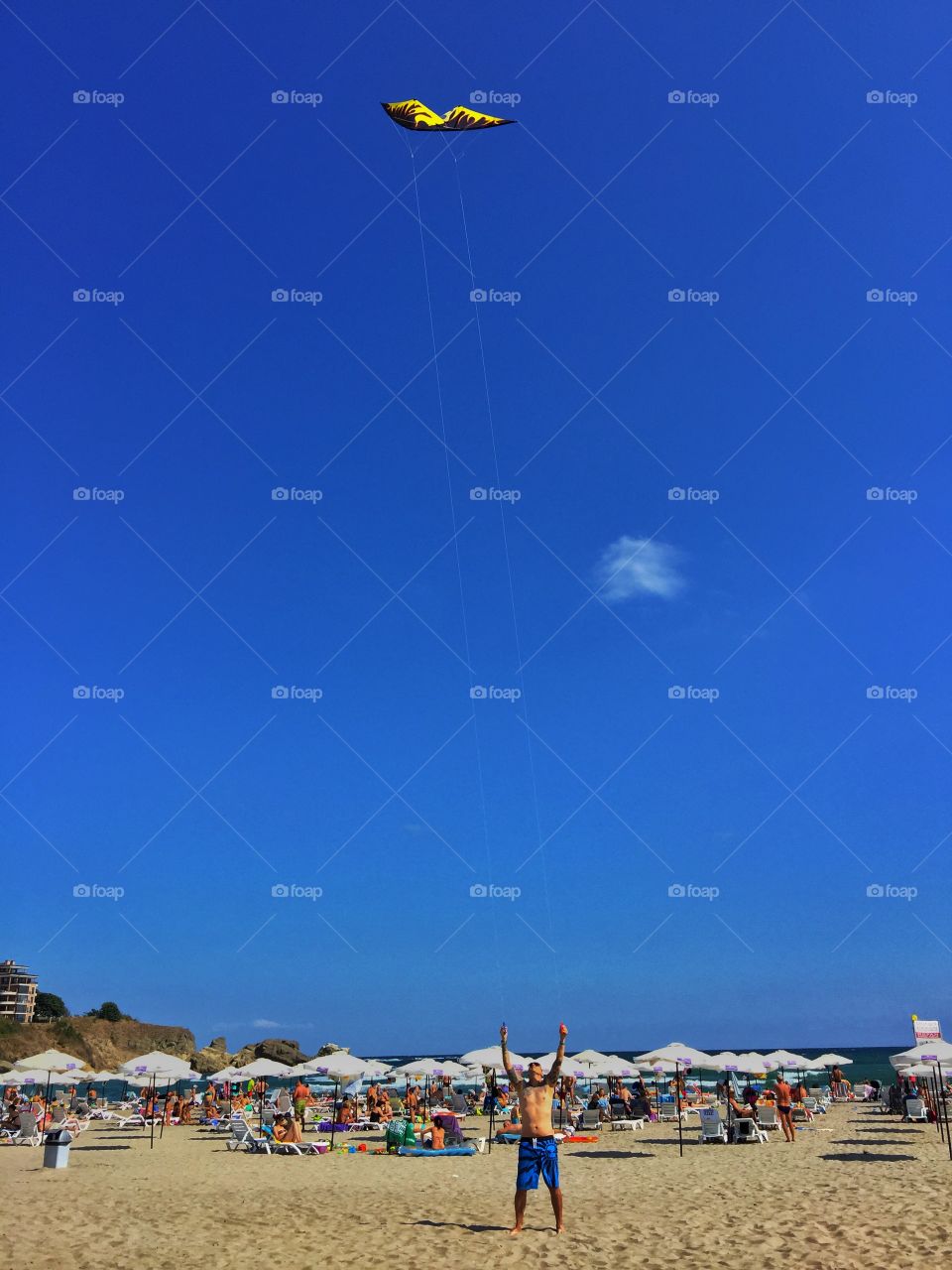 Shirtless man flying kite at beach