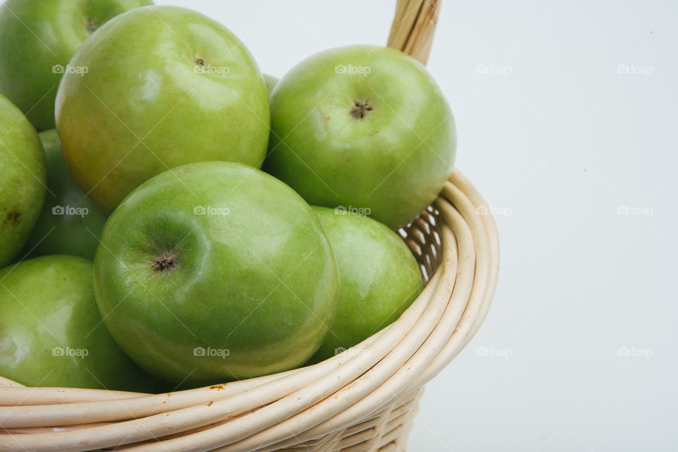 Green apples in woven basket on white background
