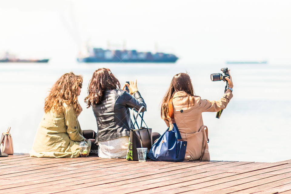 Young Girls Friends Taking Selfie And Using Mobile Phones At The Dock
