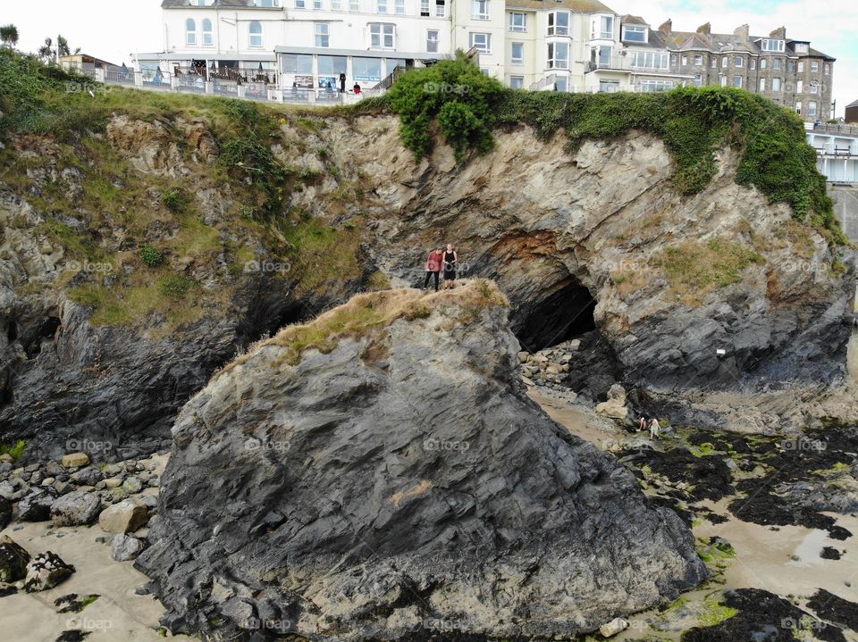 drone shot of 2 men standing on a rock on a beach in Newquay