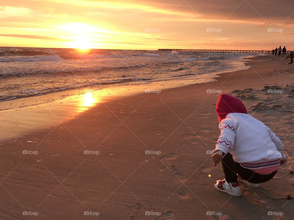 Baby draw on the sand on sunset 