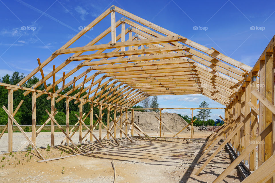 frame of a new wooden house under construction against a blue sky background
