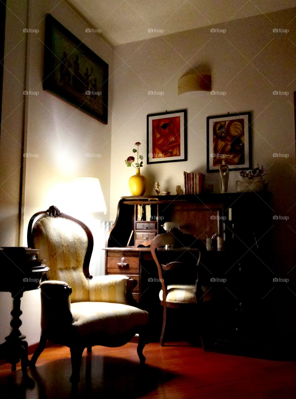 Writing desk in the living room with old restored armchairs, ethnic paintings, lamp. Cozy atmosphere.