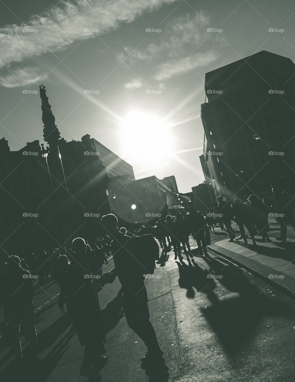 The sun goes down in London, silhouetting the buildings, the streets are full people with long shadows