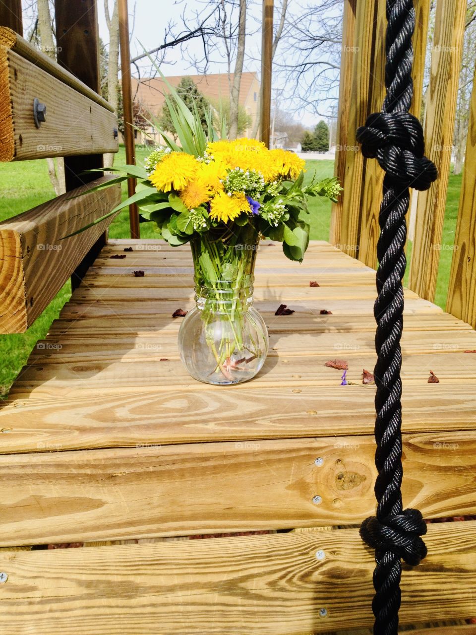 Beautiful bouquet of yellow dandelions picked by child sitting on playground equipment. 