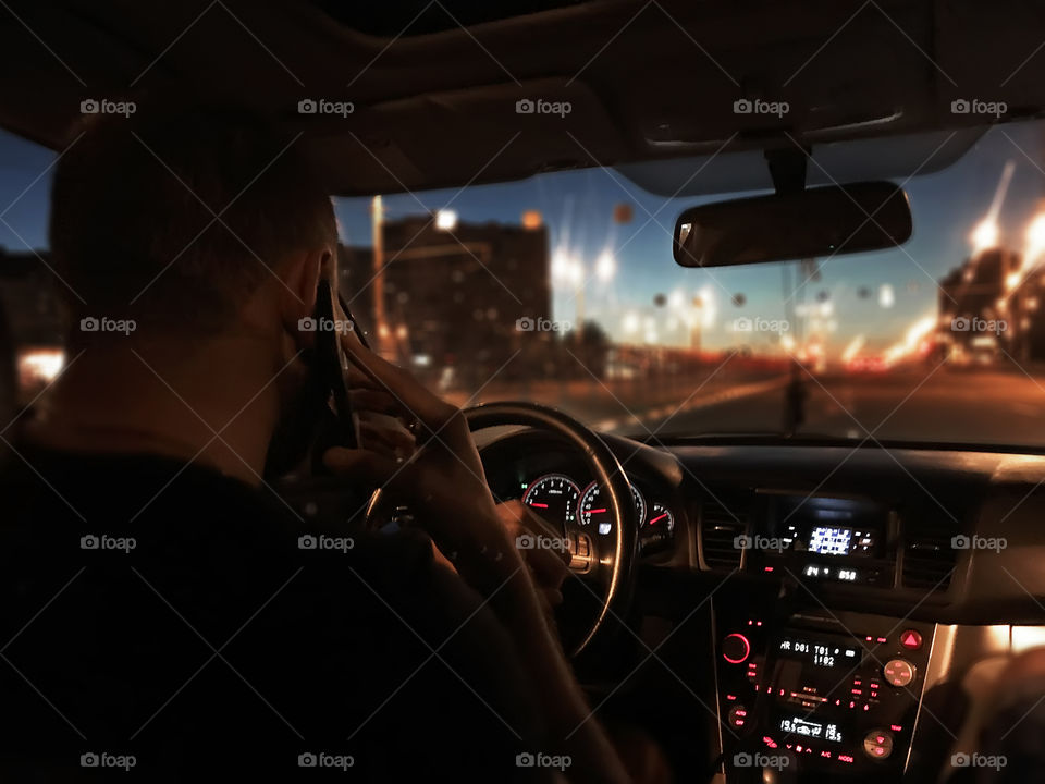 Young man driving a car by the night city road 