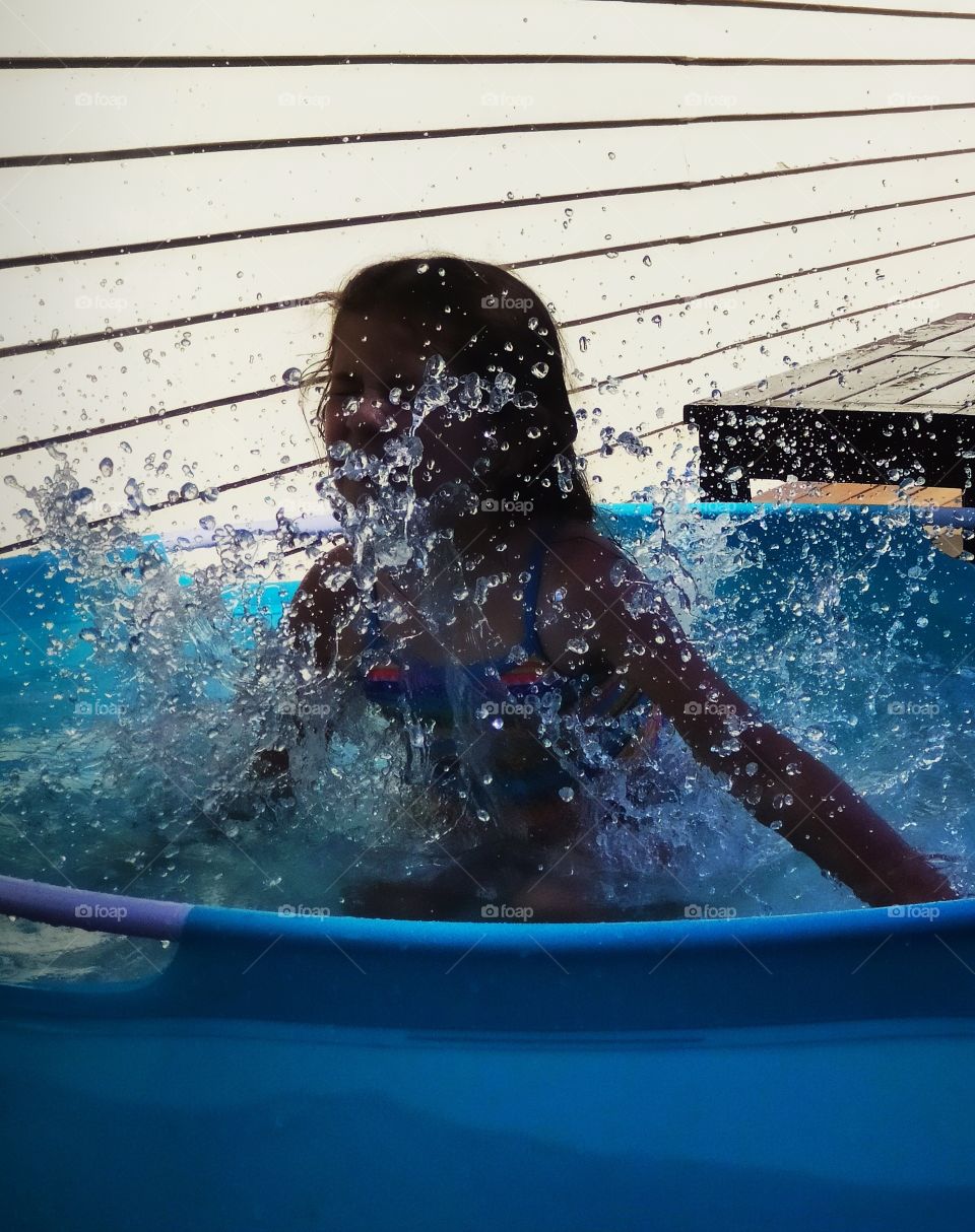 Summer time, girl making a big splash in the pool