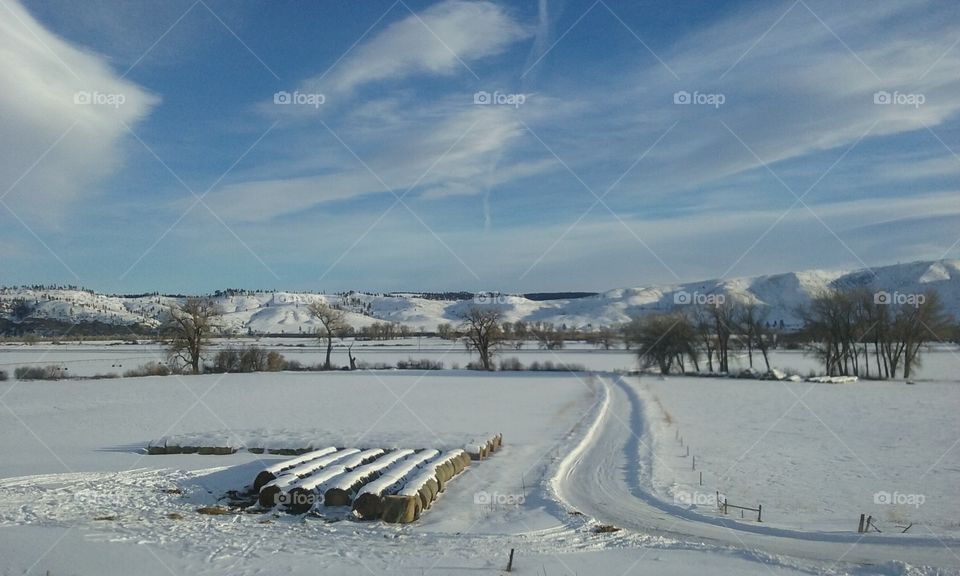 Winter on the Ranch, bails of hay and a snow covered road.