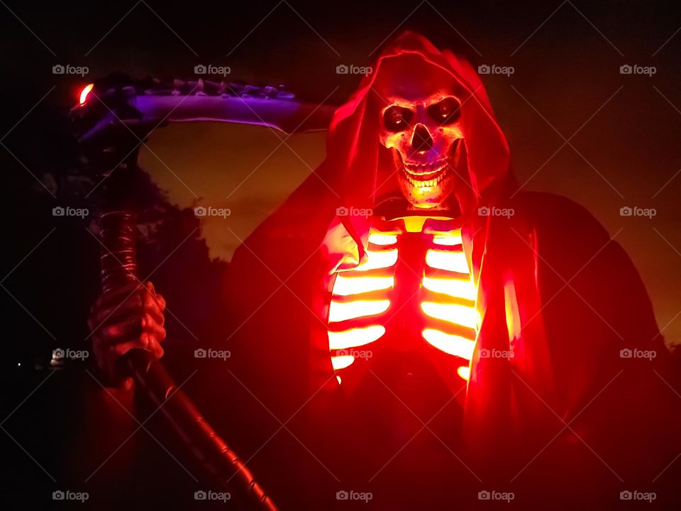 Spooky Animatronics skeleton with glowing red coming out of his chest. Displayed outdoors for Halloween by an avid animatronics collector.