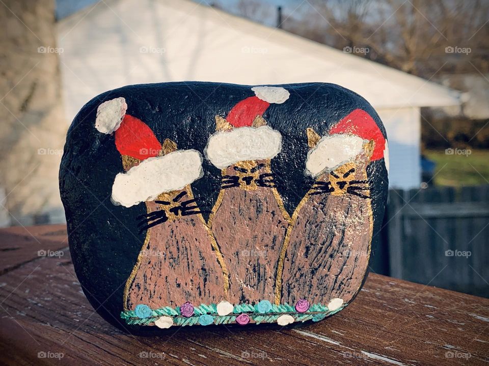 Painted rock with a holiday cat theme. Art is my take on a postcard for CatLadyBox, by artist Denise Every. Santa cats.