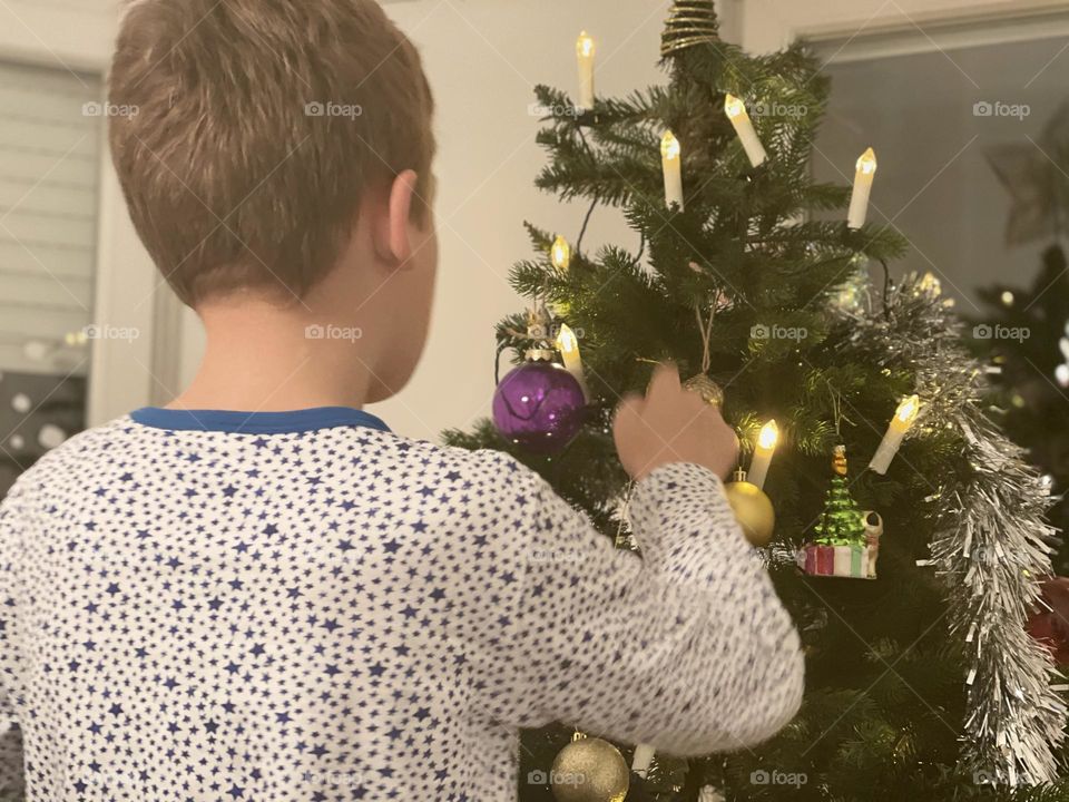 The boy decorates the Christmas tree