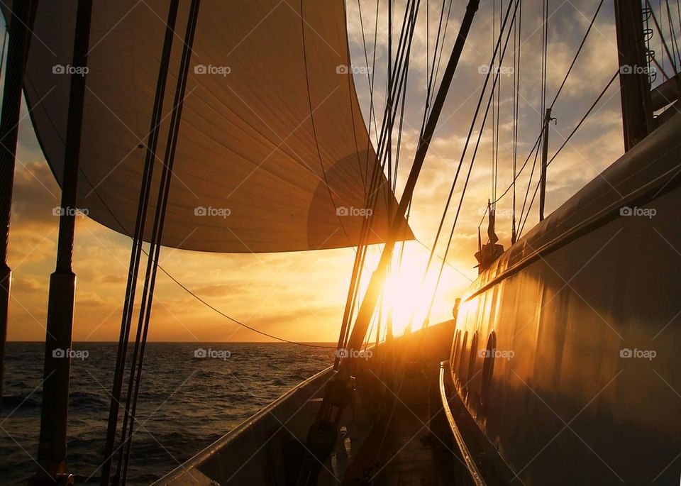 sailing in a sail ship at the ocean towards sunset