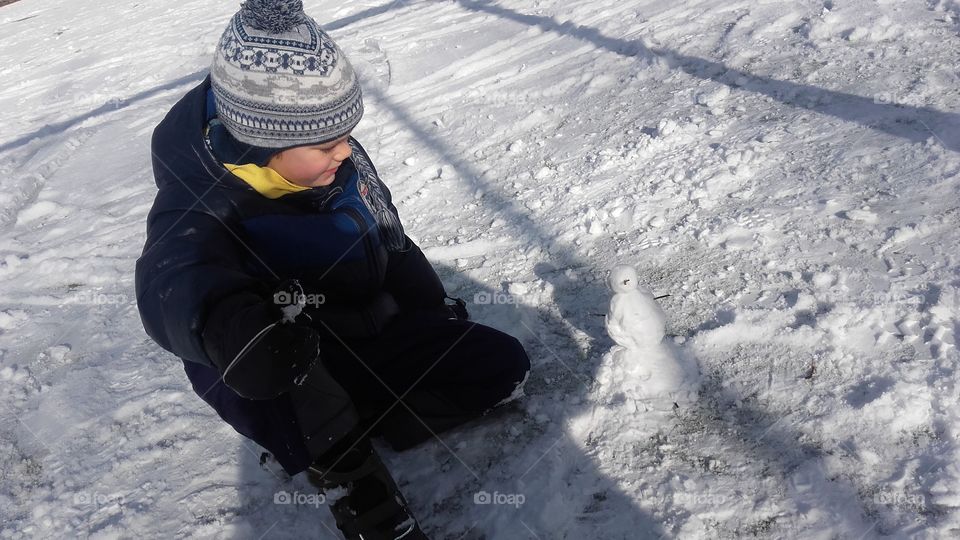 Child making snowman in winter