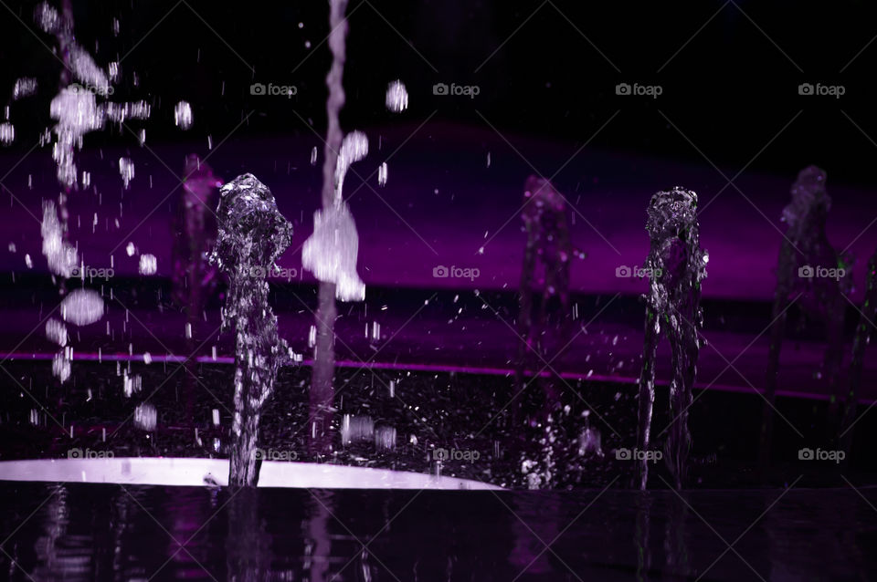 Water in motion abstract art background falling water in fountain shaped like a girl in light with water figures walking away 