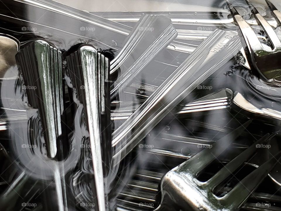 Forks under water with reflections on the water.