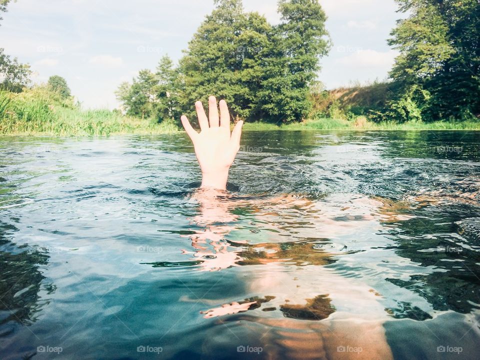 Submerged boy keeping his hand above a water