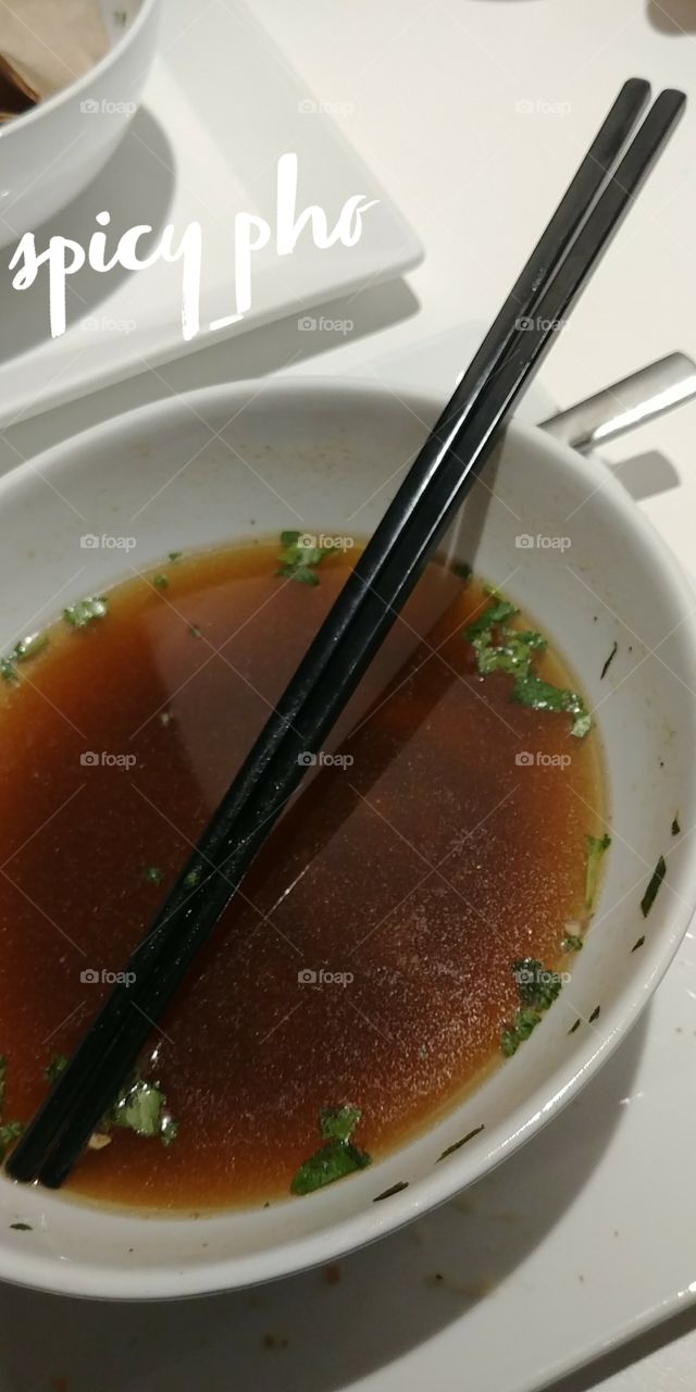 chopsticks in bowl of pho broth