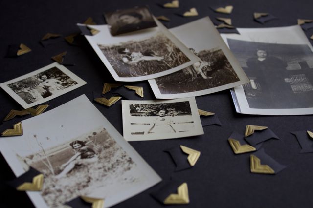 Vintage photo collection in black and white and sepia tones with gold photo mounting corners on a black surface 