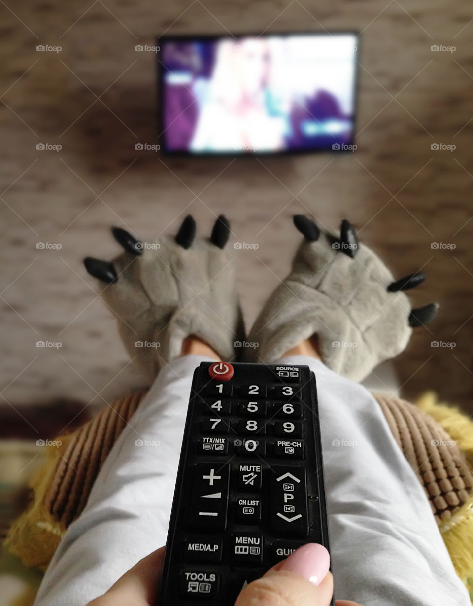 Watching television in cozy home slippers and warm knitted pants 