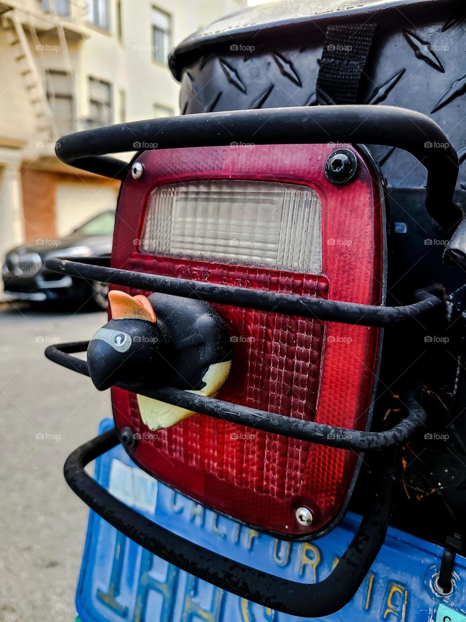 Black rubber duck stuck in the safety guard on a vehicle in the streets of San Francisco, going for a ride through this famous city