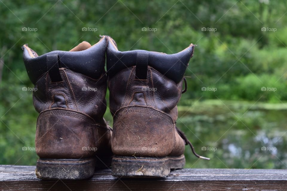 A well worn and dirty pair of hiking boots sitting outside on the cabin deck.